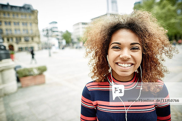 Portrait einer lächelnden jungen Frau mit Ohrhörern