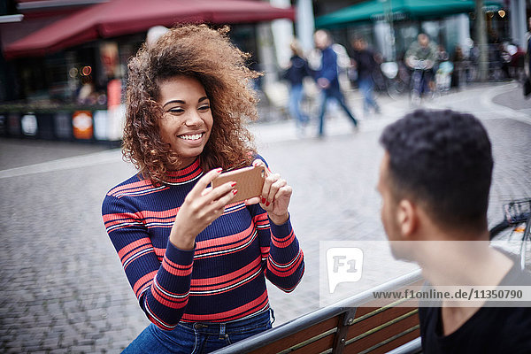 Young woman taking cell phone picture of her boyfriend