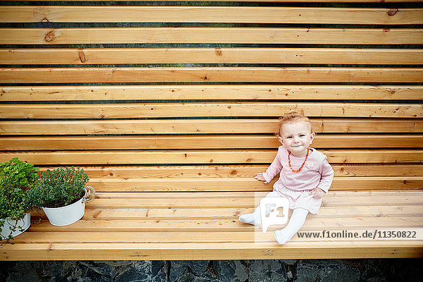 Baby sitzt auf einer Bank