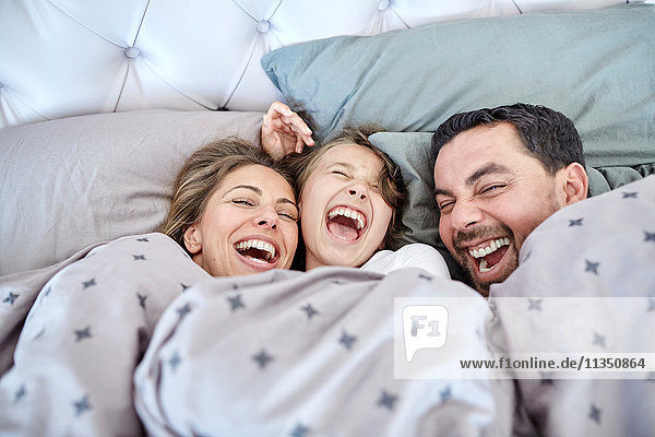 Fröhliche Eltern mit Tochter im Bett