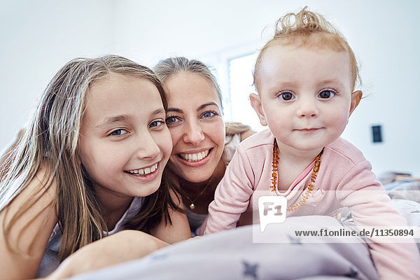 Portrait of mother with daughter and baby girl in bed