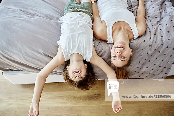 Happy mother and daughter lying in bed