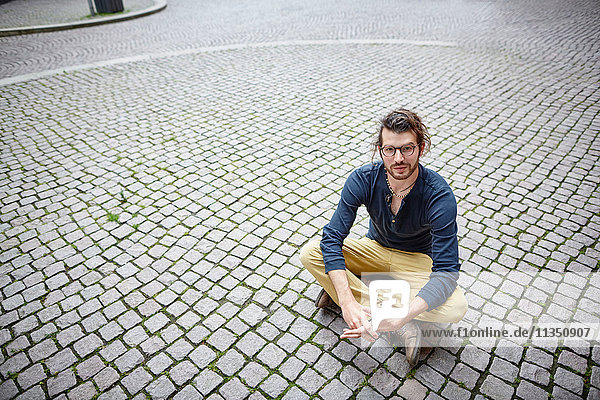 Junger Mann sitzt auf einem Platz