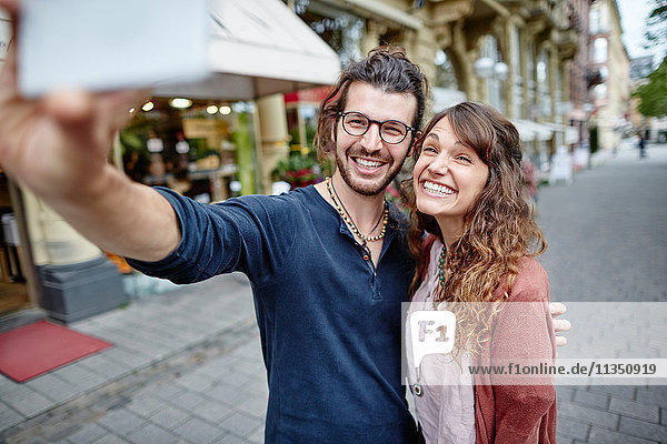 Lächelndes junges Paar macht ein Selfie in der Stadt