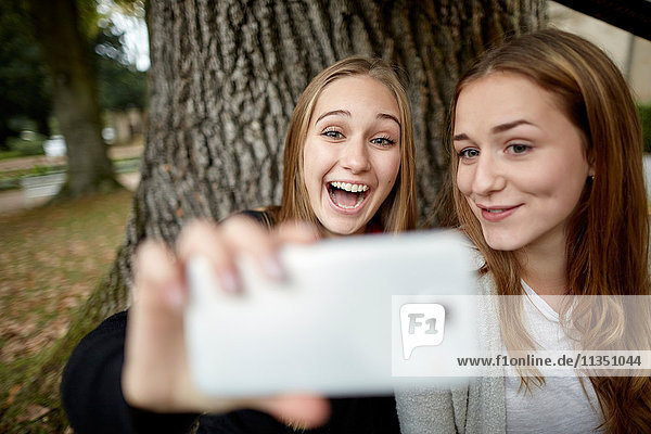 Zwei fröhliche junge Frauen machen ein Selfie im Freien