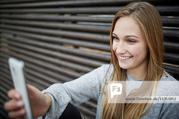 Lächelnde junge Frau schaut auf Handy