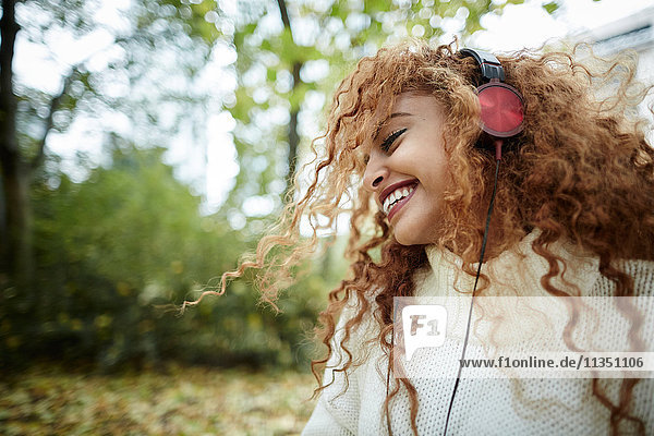 Fröhliche Teenagerin mit Kopfhörern im Park
