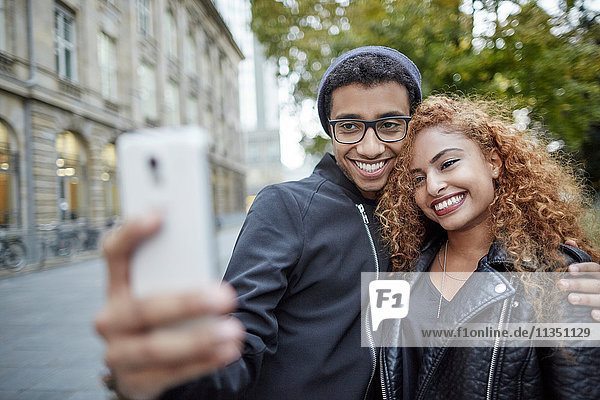 Lächelndes junges Paar macht ein Selfie im Freien