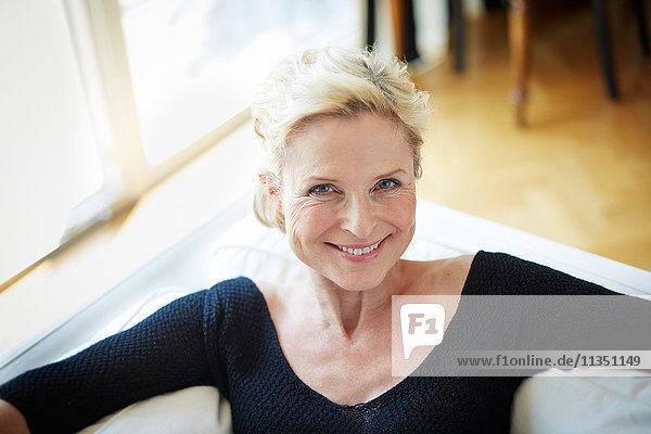 Portrait einer lächelnden reifen Frau auf einem Sofa