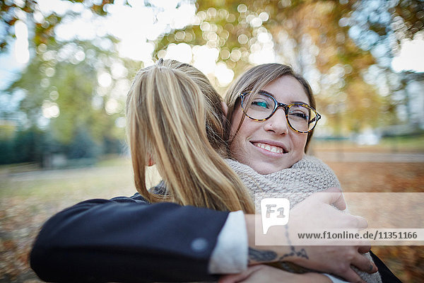 Two smiling women hugging in park