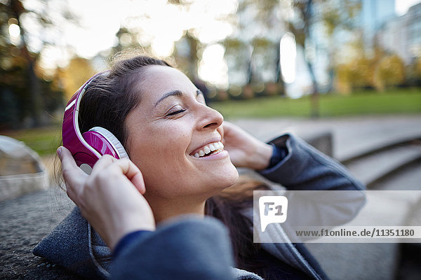 Lächelnde Frau mit Kopfhörern im Freien