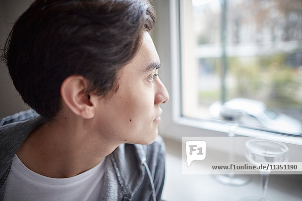 Junger Mann schaut aus dem Fenster