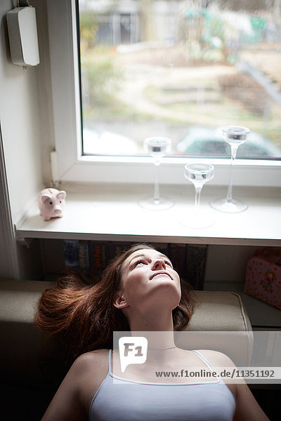 Entspannte junge Frau Zuhause schaut aus dem Fenster