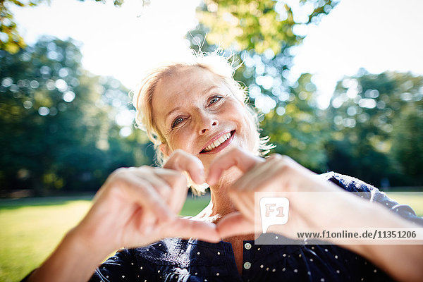 Smiling mature woman shaping heart with her hands