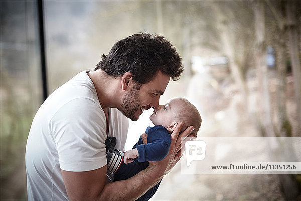 Glücklicher Vater reibt die Nase mit Baby