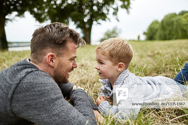 Vater und Sohn liegen auf einer Wiese und sehen sich an