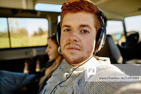 Portrait eines jungen Mannes mit Kopfhörern in einem Auto
