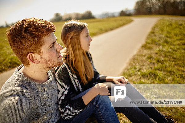Young couple sitting at country lane