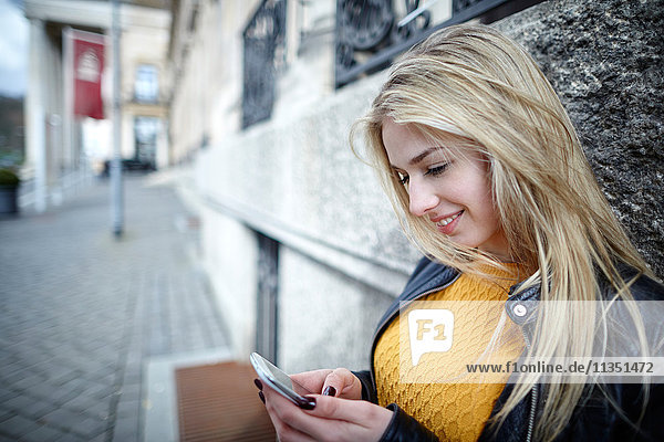 Lächelnde junge Frau schaut auf ihr Handy