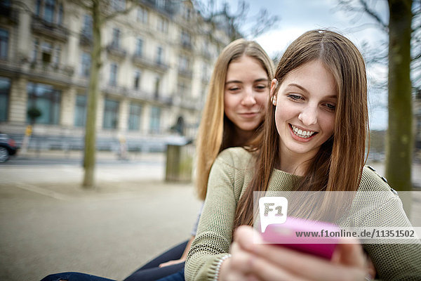 Two smiling young women with cell phone