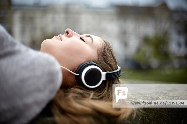 Entspannte liegende junge Frau mit Kopfhörern