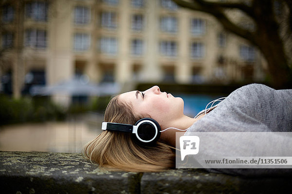Relaxed young woman wearing headphones lying down