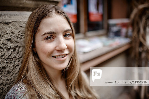 Portrait einer lächelnden jungen Frau an einer Hauswand