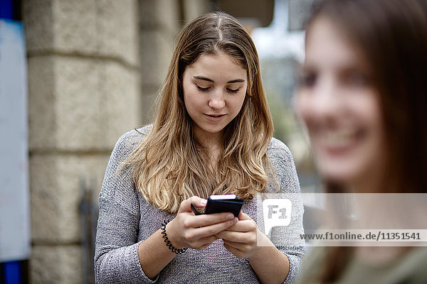 Junge Frau schaut auf ihr Handy
