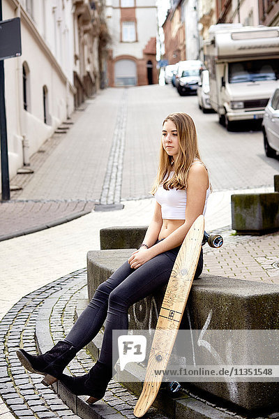 Young woman with skateboard sitting down