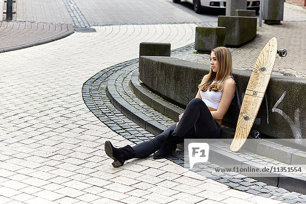 Young woman with skateboard sitting down