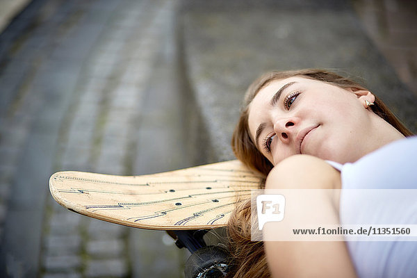 Junge Frau liegt auf einem Skateboard