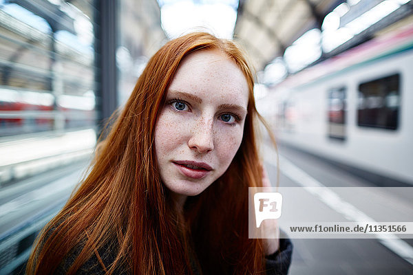 Portrait einer rothaarigen jungen Frau auf dem Bahnsteig