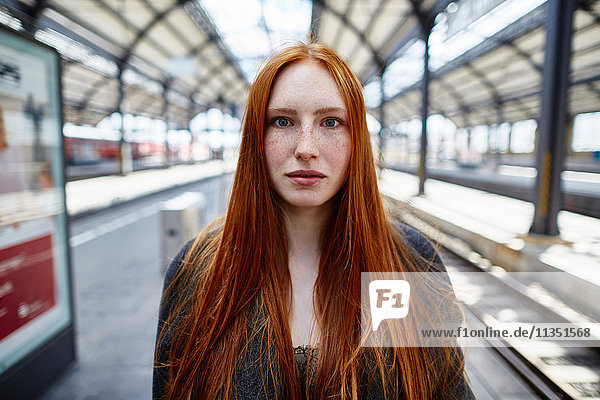 Portrait einer rothaarigen jungen Frau auf dem Bahnsteig