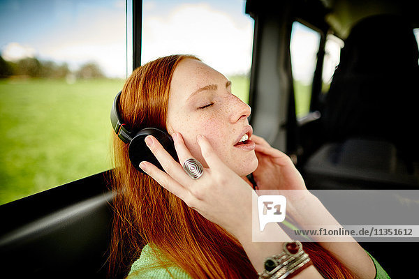 Young woman in car listening to music with headphones