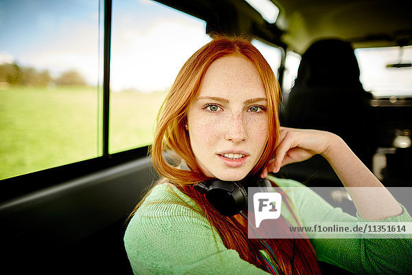 Portrait of young woman with headphones in car