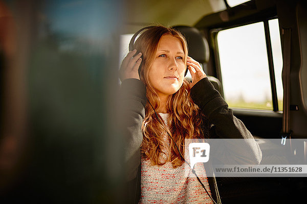 Junge Frau im Auto hört Musik mit Kopfhörern