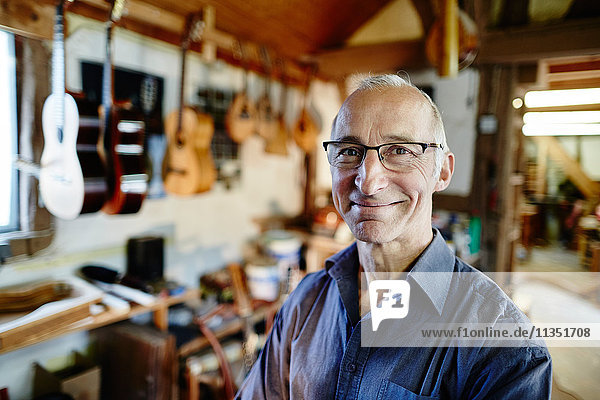Portrait of a smiling guitar maker in his workshop