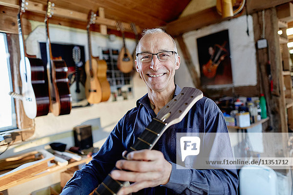 Portrait eines lächelnden Gitarrenbauers in seiner Werkstatt
