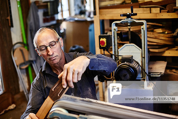 Gitarrenbauer schleift ein Griffbrett in seiner Werkstatt