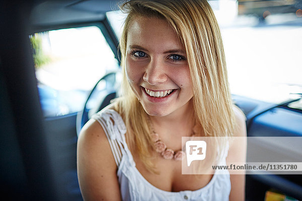 Portrait einer lächelnden jungen Frau in einem Auto