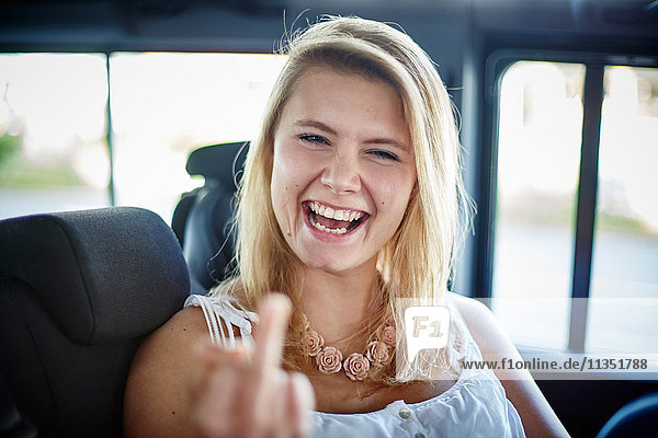 Portrait einer verspielten jungen Frau in einem Auto