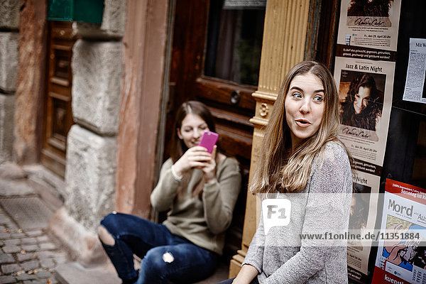 Junge Frau  die mit ihrem Handy ein Foto von einem Freund in einem städtischen Gebäude macht