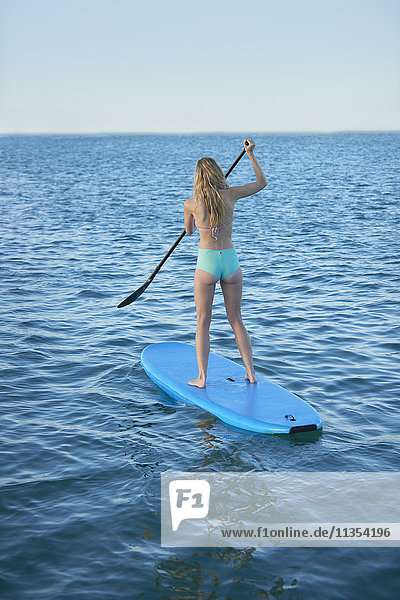 Junge Frau im Bikini Paddeln im Sommer Ozean