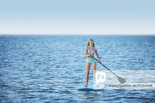 Junge Frau beim Bikini-Paddeln auf dem Sommer-Ozean