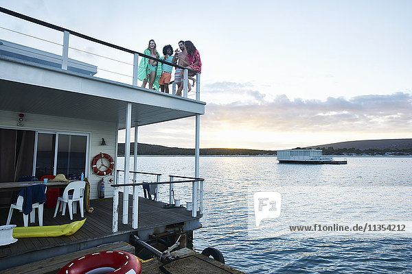 Junge erwachsene Freunde  die auf dem Deck des Sommerhausbootes auf dem Meer herumhängen