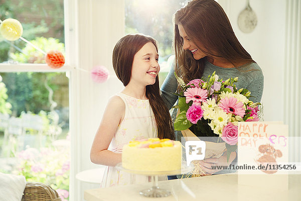 Affectionate daughter giving flower bouquet to mother on Mother’s Day
