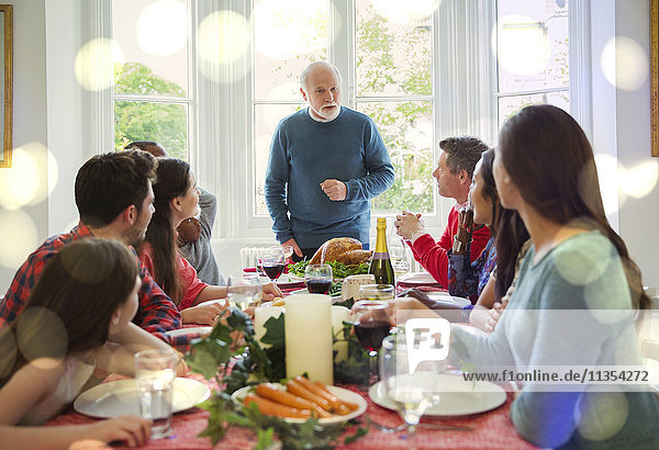 Grandfather preparing to carve Christmas turkey at dinner table