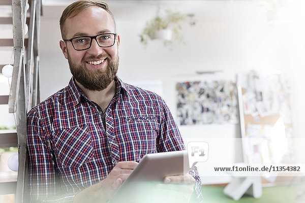 Portrait lächelnder männlicher Designprofi mit digitalem Tablett im Büro