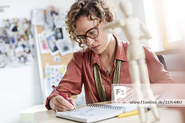 Fokussiertes weibliches Design professionelles Skizzieren im Notebook im Büro