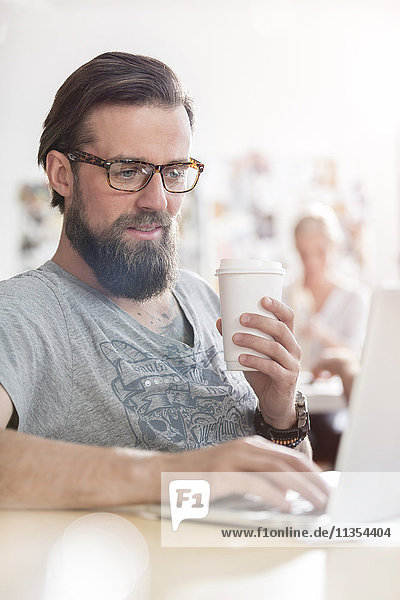 Männliches Design professionelles Kaffeetrinken am Laptop